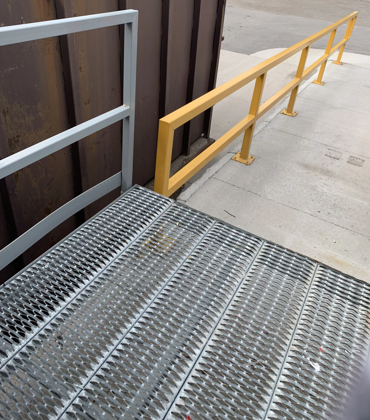 Yellow steel safety barrier guarding an outdoor concrete walkway in Barrie, Ontario