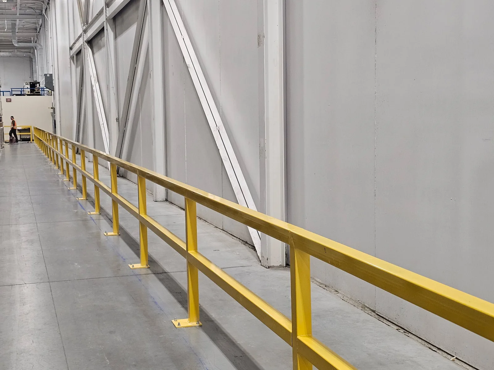 Yellow structural steel safety barrier installed along a warehouse wall in Markham, Ontario