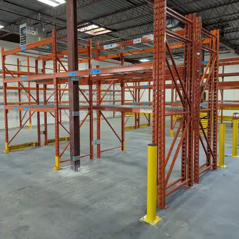 Yellow steel bollards protecting pallet racking