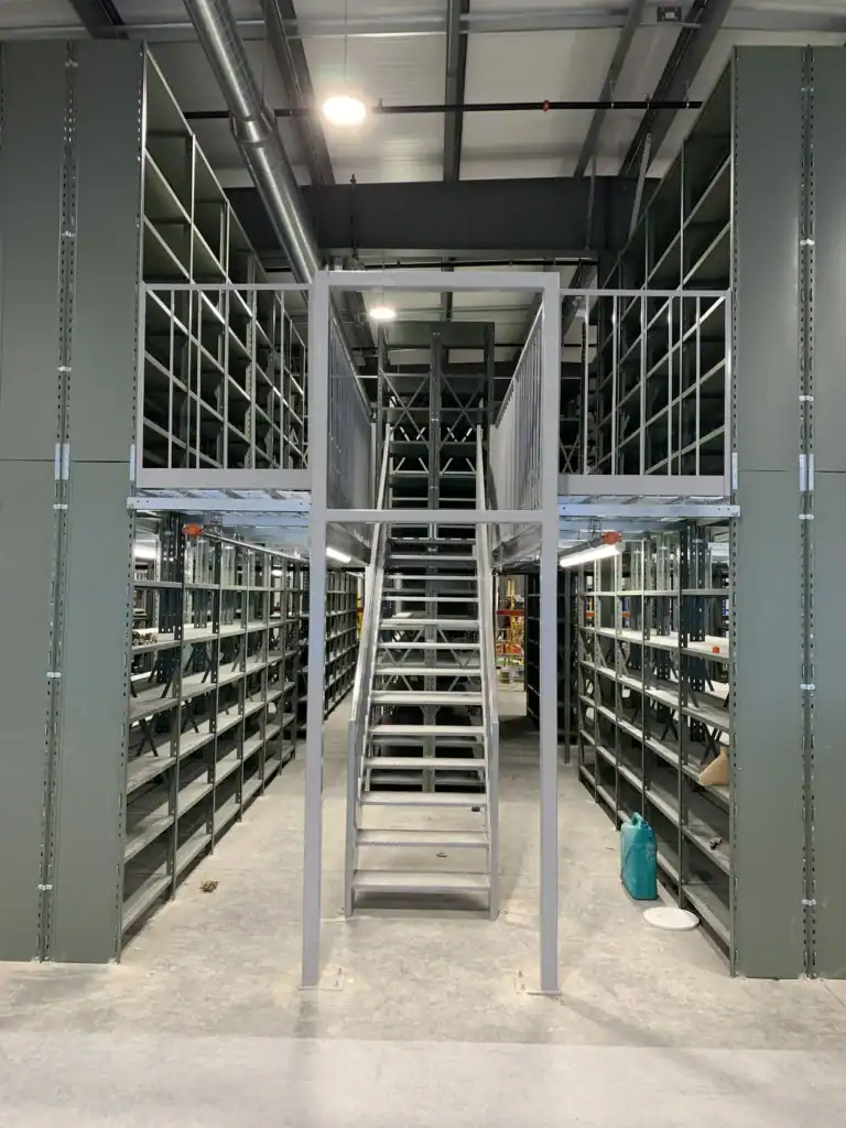 Staircase providing access to the upper level of a shelving installation