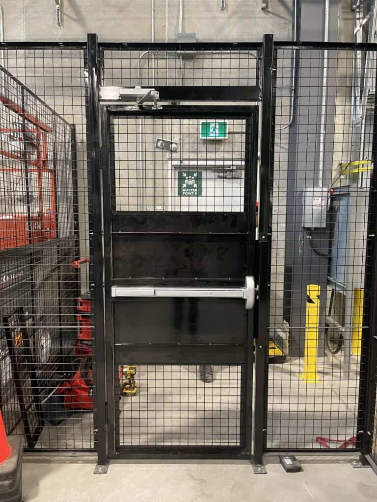 Wire mesh partition door with push bar exit hardware
