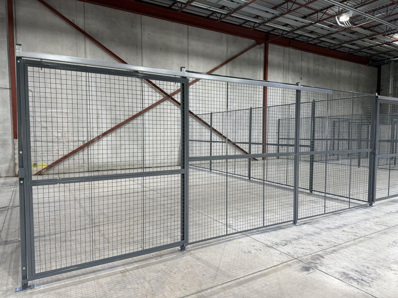 Grey wire mesh partition lock-up with sliding gate in a warehouse